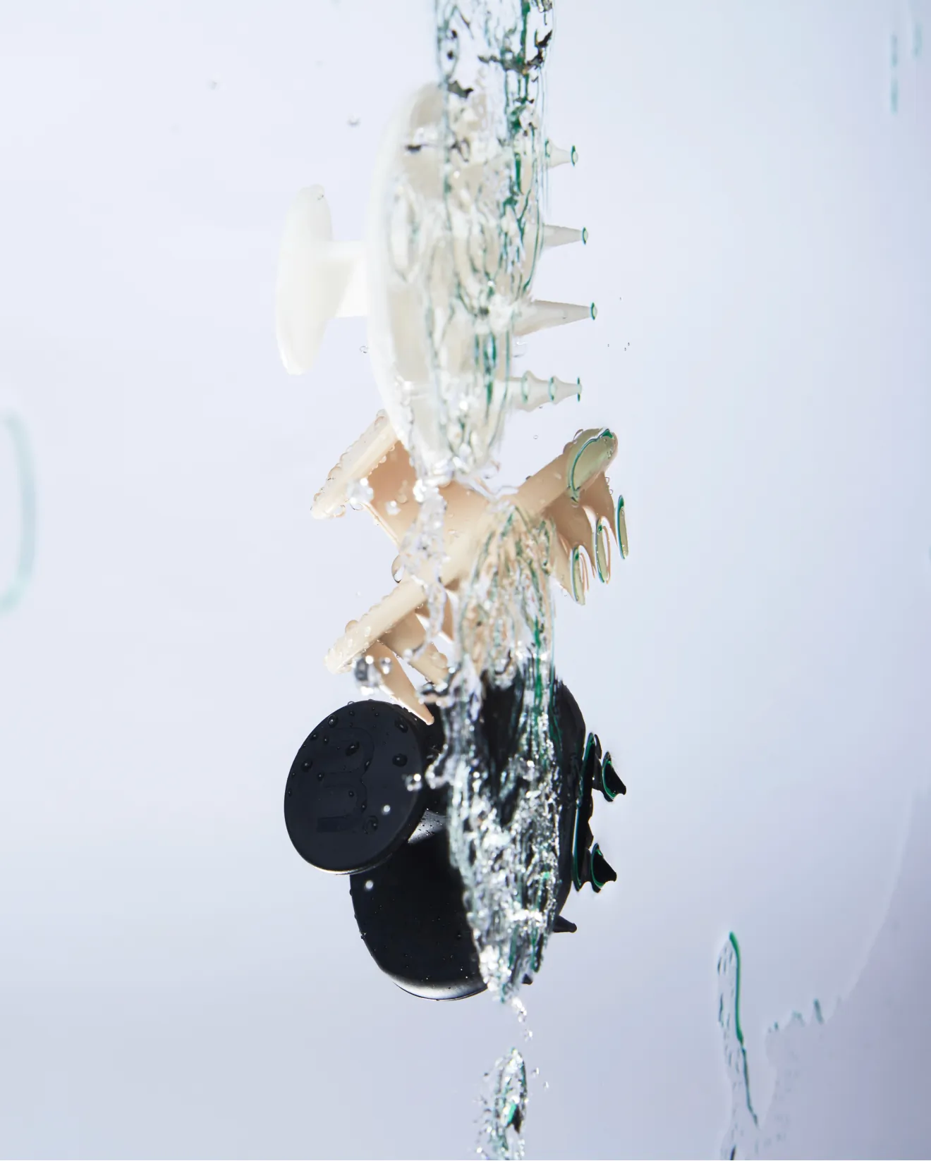 Plastic mechanical model with circular discs and pegs, partially submerged with water splashing around the rotating assembly.