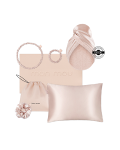 Soft pink satin accessories including two scrunchies, a pair of hoop earrings, a silk pillow, a satin drawstring pouch, and a pale pink card with 'mon mou' embossed.