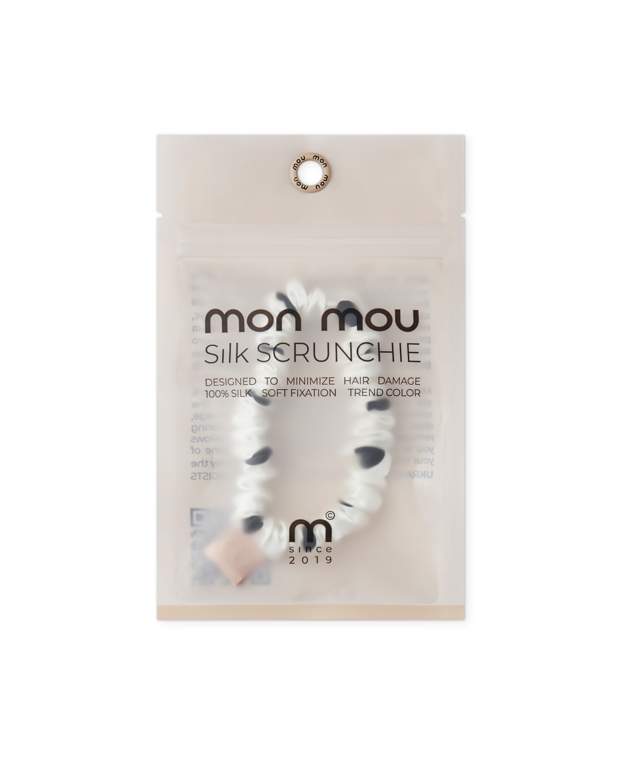 Close-up of a translucent packaging for Mom Mou Silk Scrunchie, with a circular top hole and brand text visible.