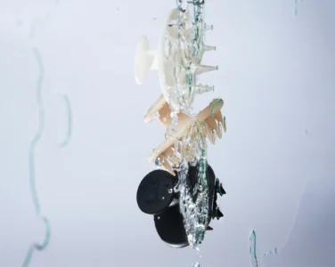 Abstract water-splashed sculpture featuring a circular wheel with green-tipped spikes.
