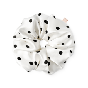 White satin hair scrunchie with black polka dots tied in a knot.