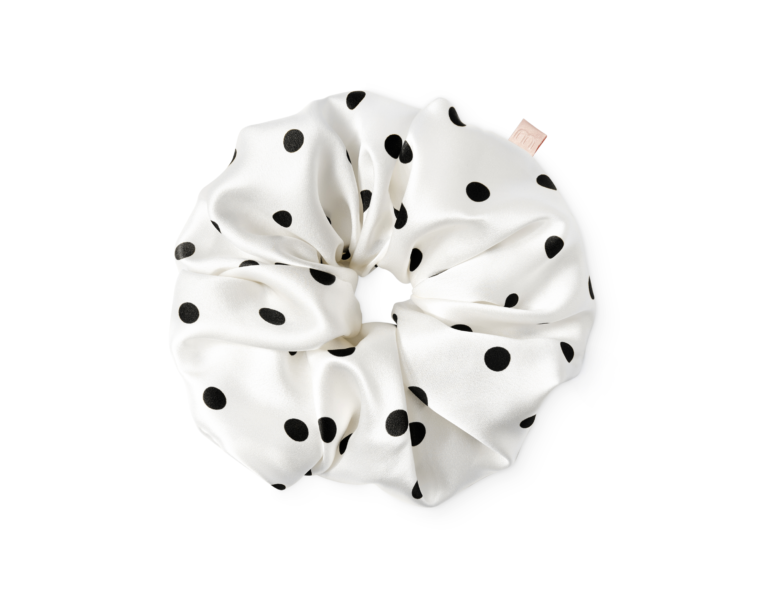 White satin hair scrunchie with black polka dots tied in a knot.