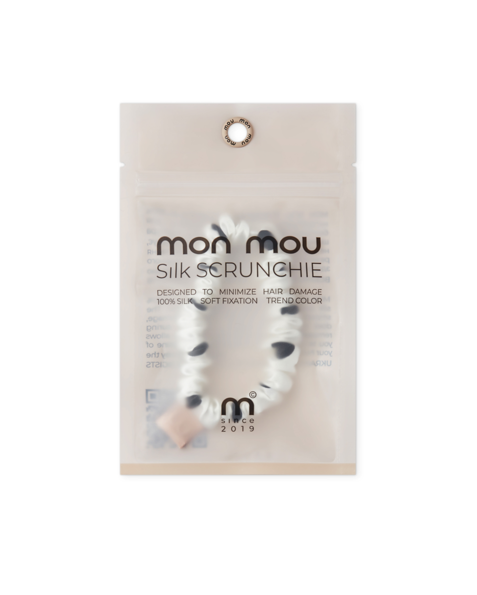 Close-up of a translucent packaging for Mom Mou Silk Scrunchie, with a circular top hole and brand text visible.