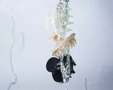 Abstract water-splashed sculpture featuring a circular wheel with green-tipped spikes.