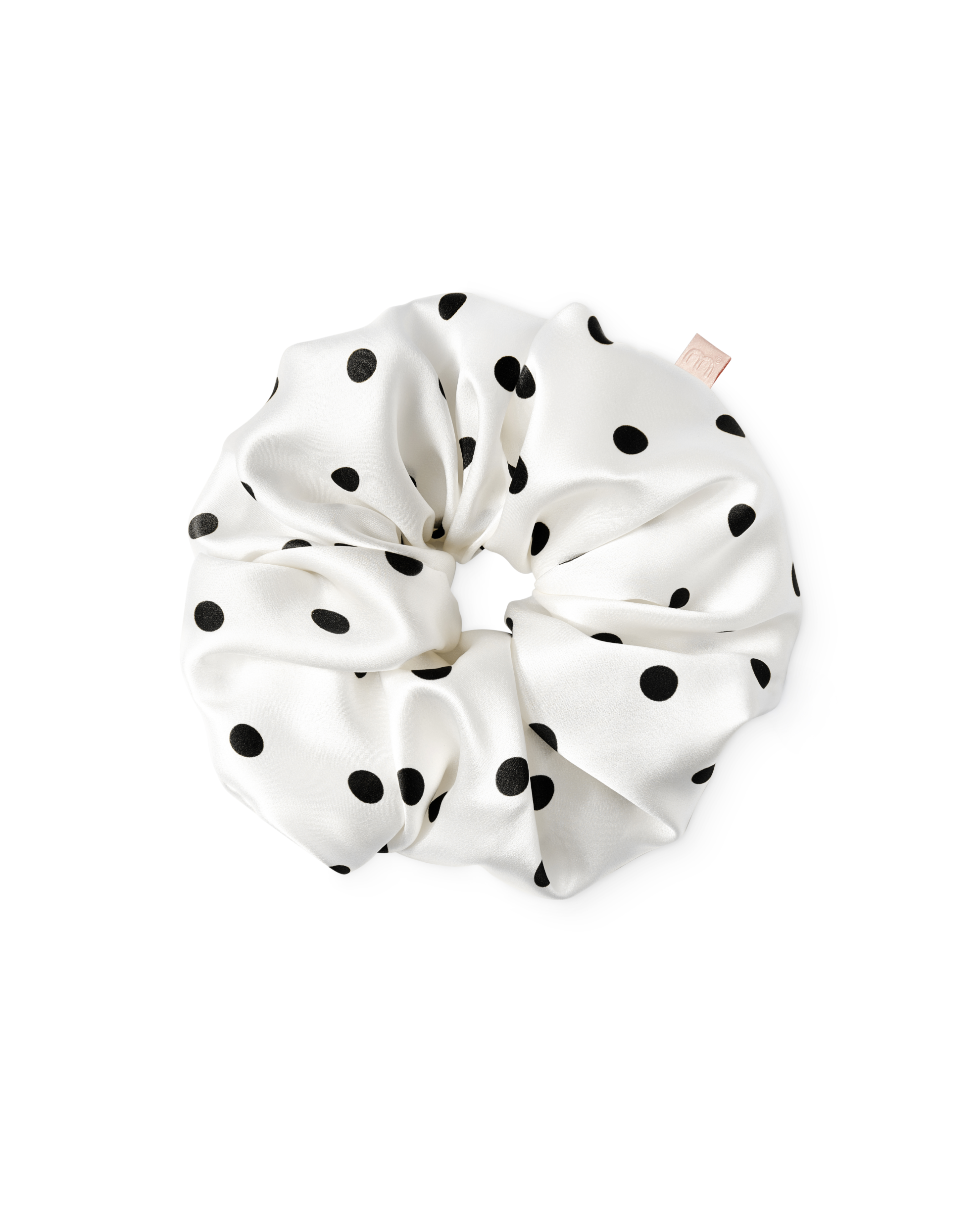 White satin hair scrunchie with black polka dots, gathered in a circular shape against a white background.