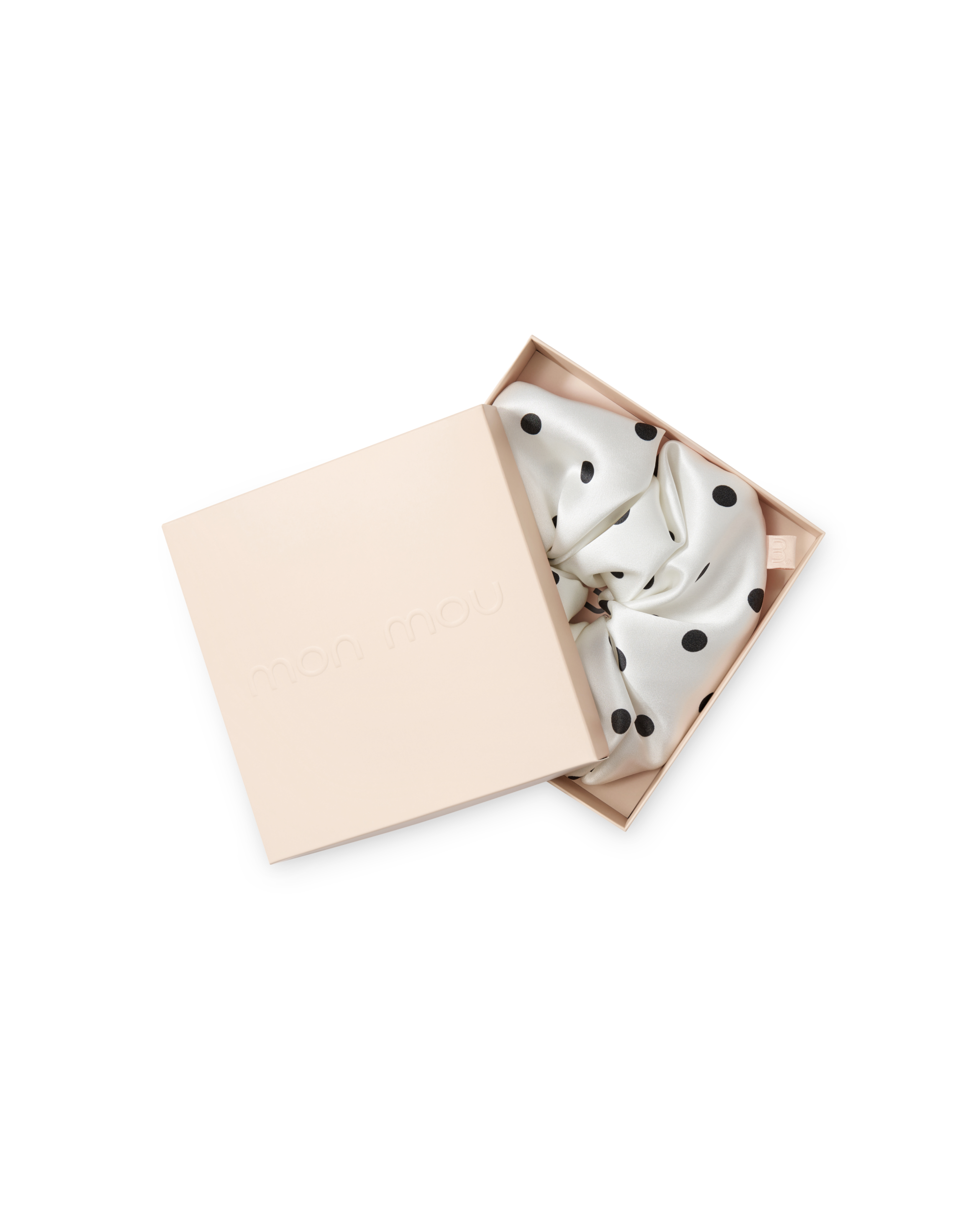 Open blush-pink gift box with a white satin scarf featuring black polka dots spilling out of the lid.