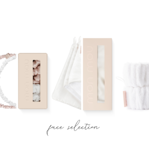 Flat lay of blush pink beauty boxes, fabric headbands, ribbons, towel, and spa accessories arranged in a row against a white background, soft and elegant.