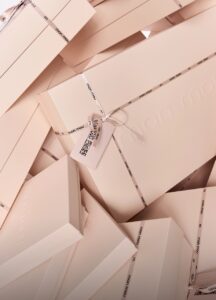 Pile of pale beige gift boxes wrapped with white ribbons and "mon mou" branding on the ribbons.