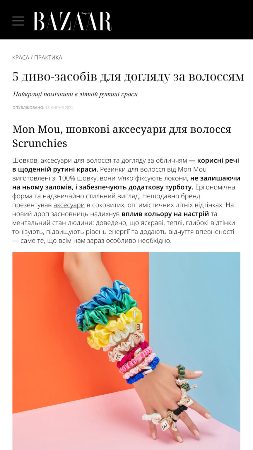 Close-up of a hand wearing many colorful scrunchies on the fingers and wrist, set against an orange and light blue background.