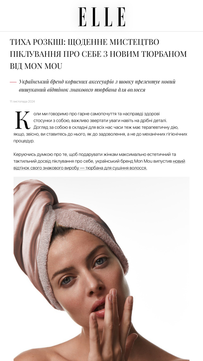 Close-up of a woman wearing a pink satin headwrap against a white background, touching her face gently.
