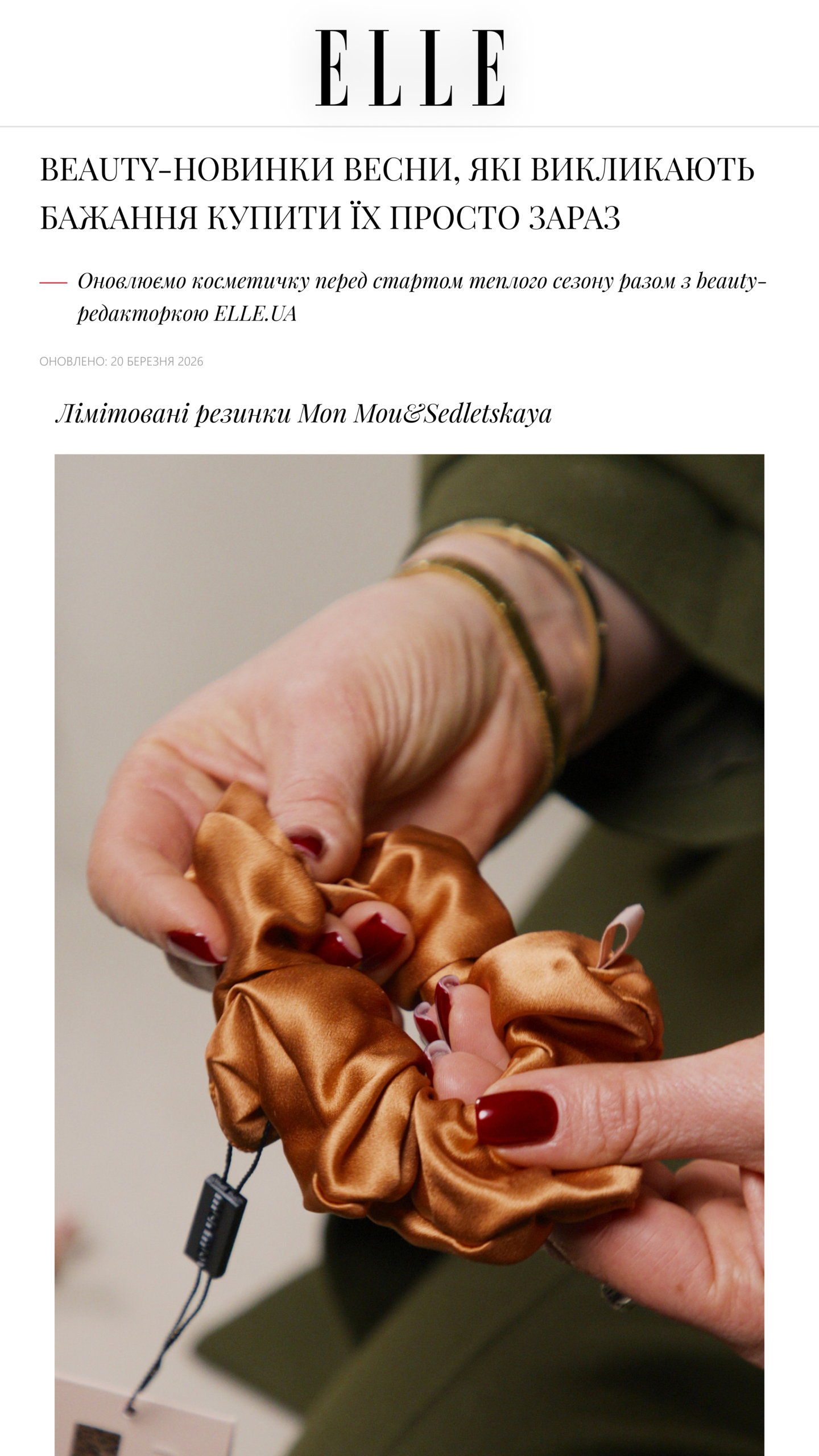 Close-up of hands holding a brown satin scrunchie with a hair tie and tag visible.
