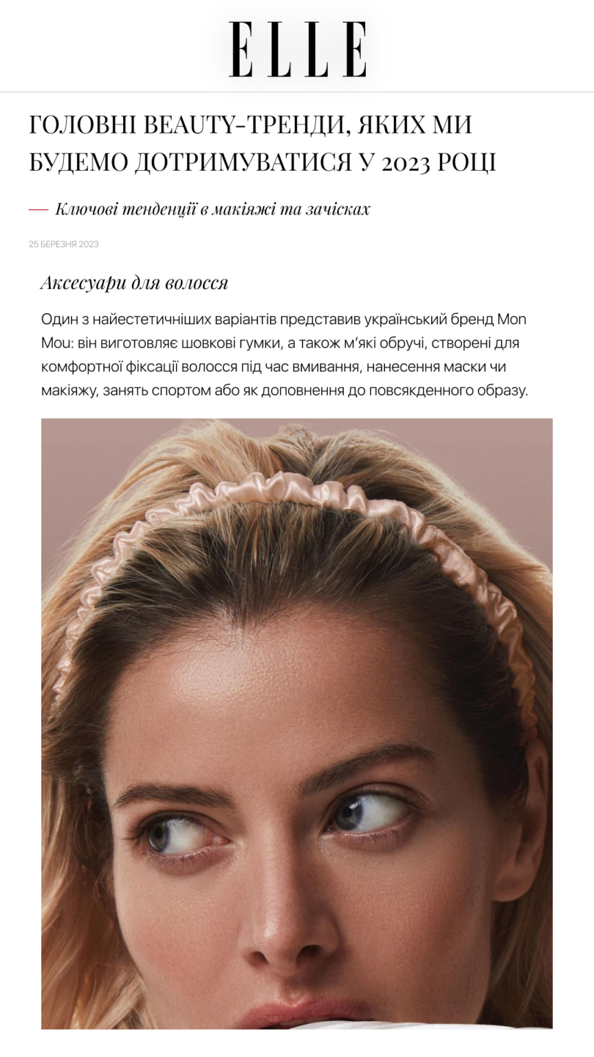 Close-up of a woman's face wearing a pale pink ruched headband, hair pulled back, visible blue eye looking to the side (beauty article image).