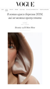 Close-up of a woman's face, blue eye visible, hooded in beige satin fabric; fashion editorial image.